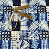 A brass measuring tape is laid across a blue and white patterned fabric, showing the texture of the cotton material.