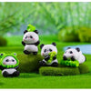 A set of cute resin panda figurines in various colors sitting on green grass.
