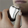 A hand holds a silver electric shaver, showing the device's design and texture.