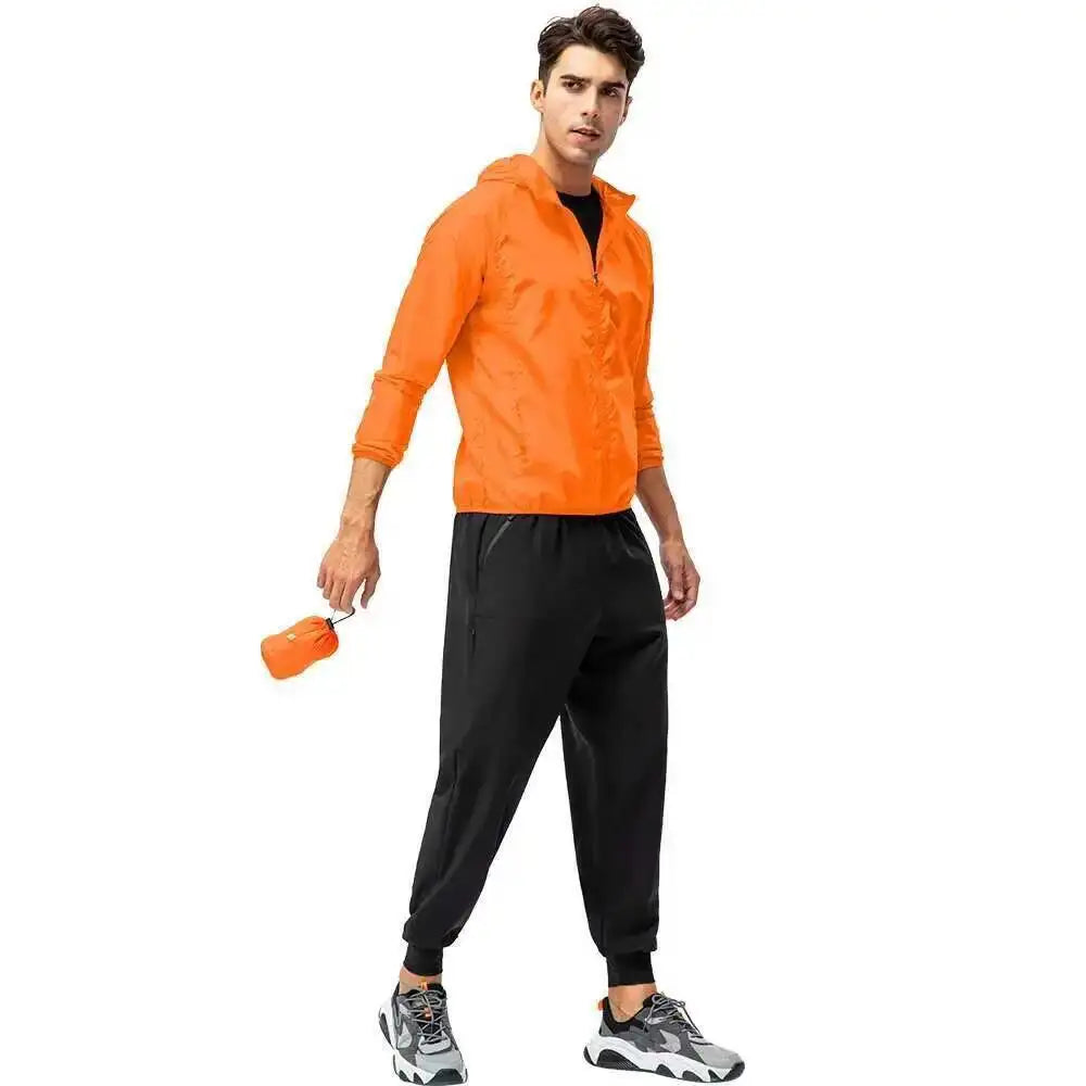 A male model wearing an orange waterproof windbreaker jacket and black pants.