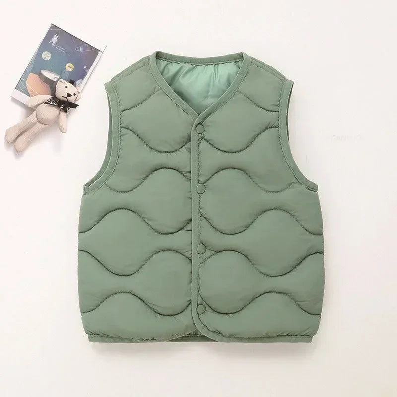 A solid green quilted vest for a child, displayed next to a small stuffed animal.