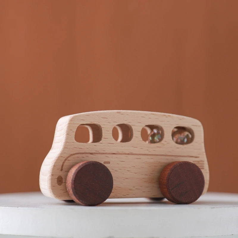 A light wood wooden cart toy with round wheels and windows is shown against a blurred brown background.