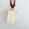 A cream-colored baby cotton sleeveless jumpsuit bodysuit set hanging on a wooden hanger.