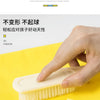 A hand is using a light-colored brush on a yellow fabric, demonstrating the durability of a product.