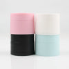 Three refillable travel face cream jars in pink, white, and light blue with leak-proof lids.