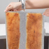 A hand is holding a square, textured cleaning cloth with a brown and gray striped pattern under a faucet.