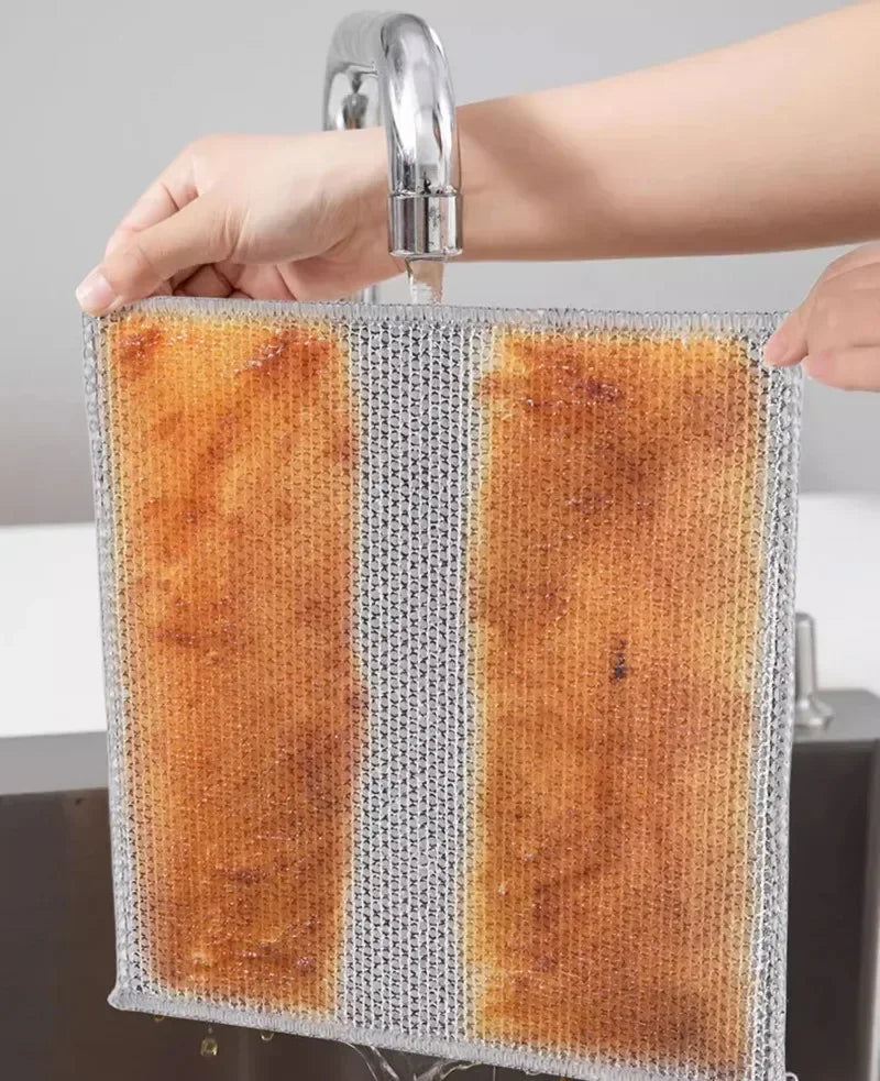 A hand is holding a square, textured cleaning cloth with a brown and gray striped pattern under a faucet.