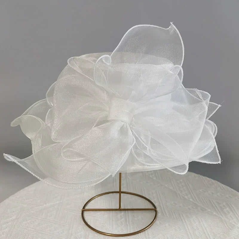 White wide brim organza sun hat with ruffled mesh detail displayed on a stand.