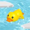 A yellow bath toy shaped like a duck floating in blue water with white blocks nearby.