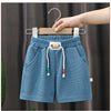 Light blue kids beach shorts with an elastic waist and wooden hanger