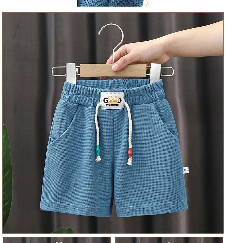 Light blue kids beach shorts with an elastic waist and wooden hanger