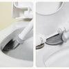 A wall-mounted silicone toilet brush set with a flat head is shown cleaning inside a white toilet bowl.