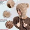 Eine Frau trägt eine beige Strickmütze mit flauschigem Rand und angenähtem Schal.