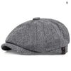 A grey and black patterned newsboy cap is shown from the side.