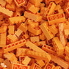 A close-up view of a bulk pack of classic building bricks in various shades of orange and yellow.