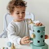 A toddler is interacting with a light green Montessori screwdriver board toy featuring magnetic screws.