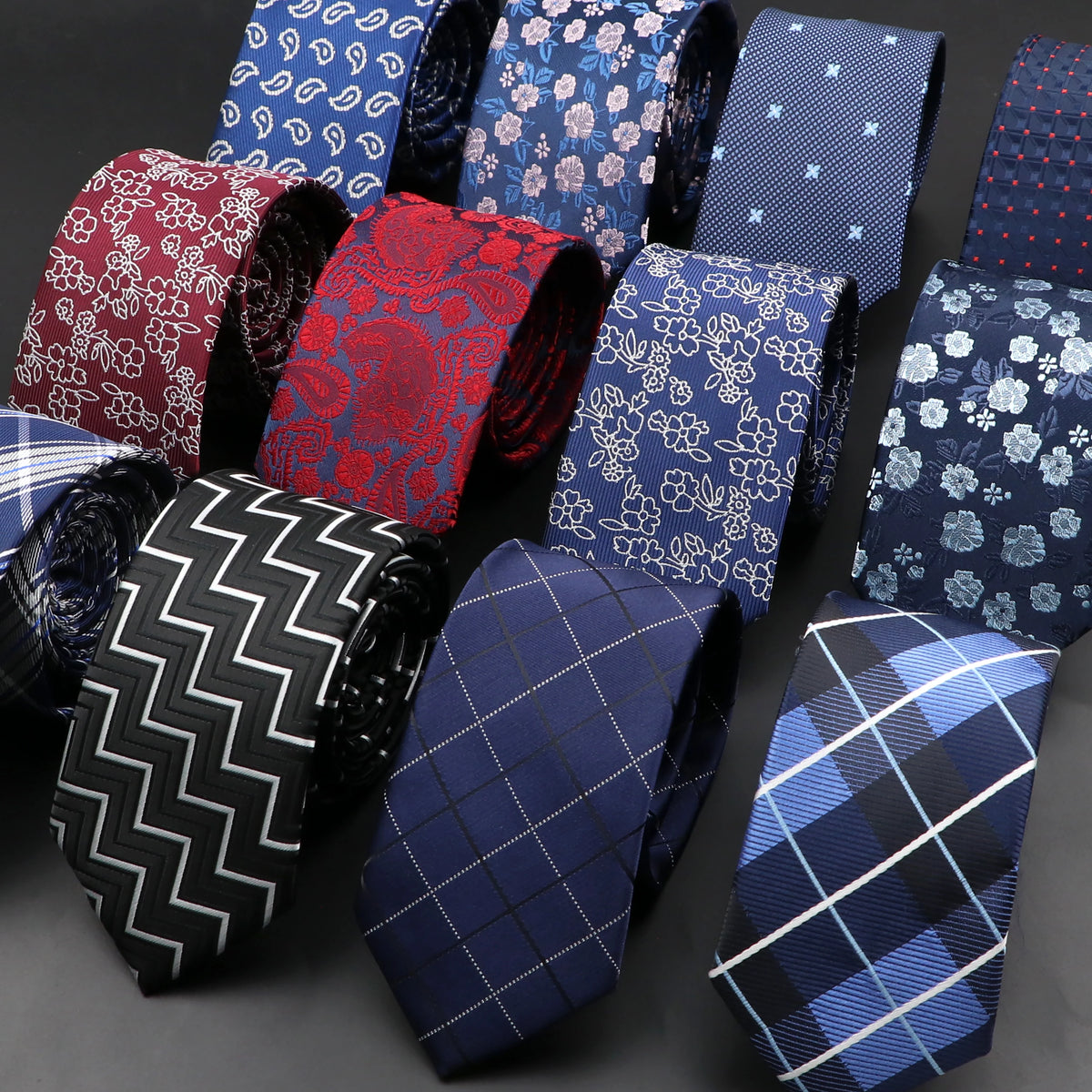 Colección de corbatas estampadas de varios colores y diseños sobre una superficie oscura.