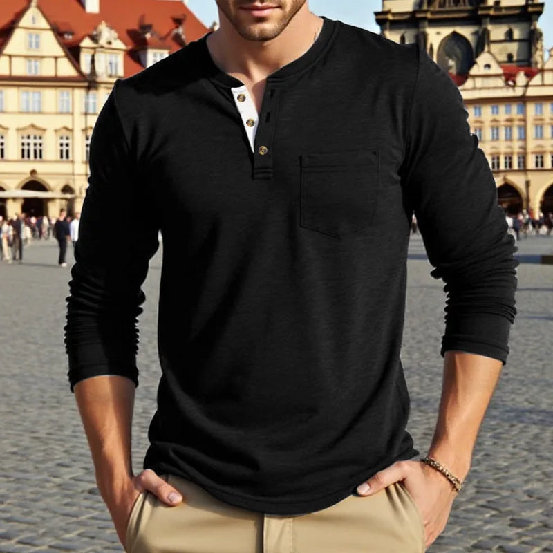 A man wearing a black long-sleeve casual shirt with a chest pocket and khaki pants outdoors.