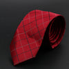 Corbata roja oscura con patrón de cuadrícula blanca, enrollada sobre fondo oscuro.
