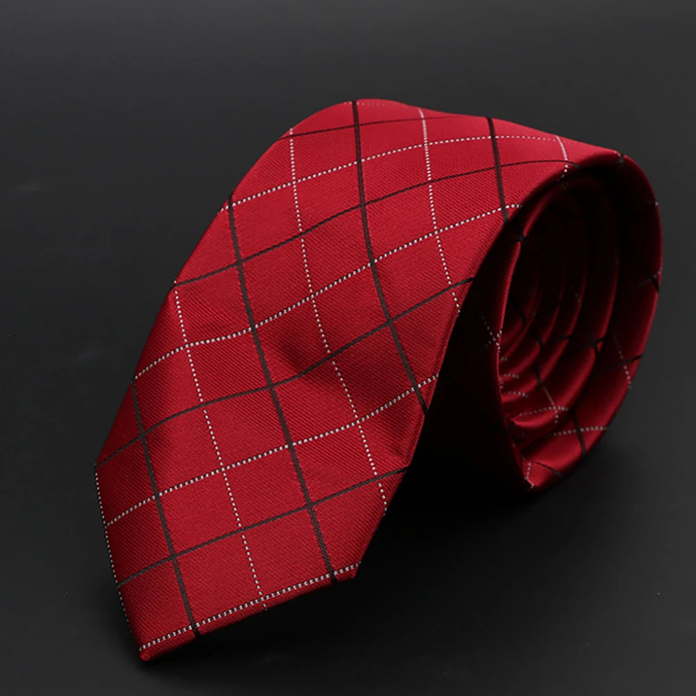 Corbata roja oscura con patrón de cuadrícula blanca, enrollada sobre fondo oscuro.