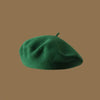 A close-up view of a deep green wool beret hat.