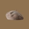 A close-up view of a classic wool beret hat in a muted beige or taupe color.