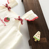 White kids summer pinafore dress with a strawberry embroidery and pink ruffle detail