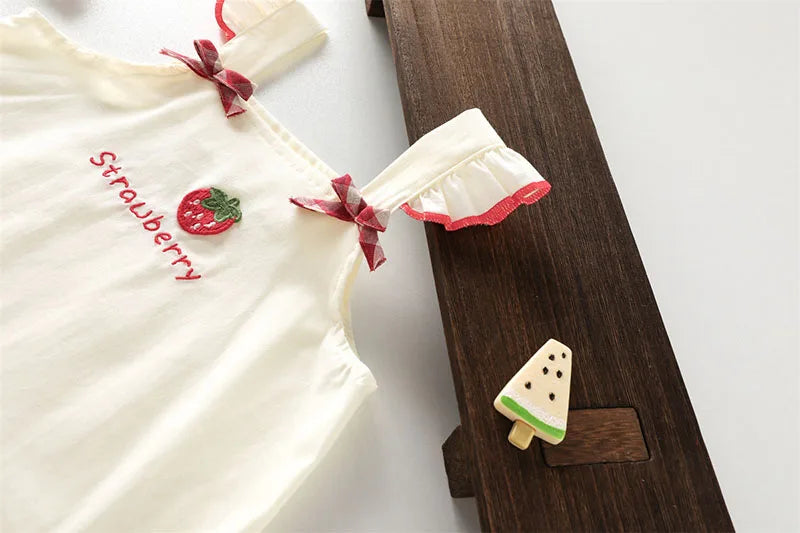 White kids summer pinafore dress with a strawberry embroidery and pink ruffle detail