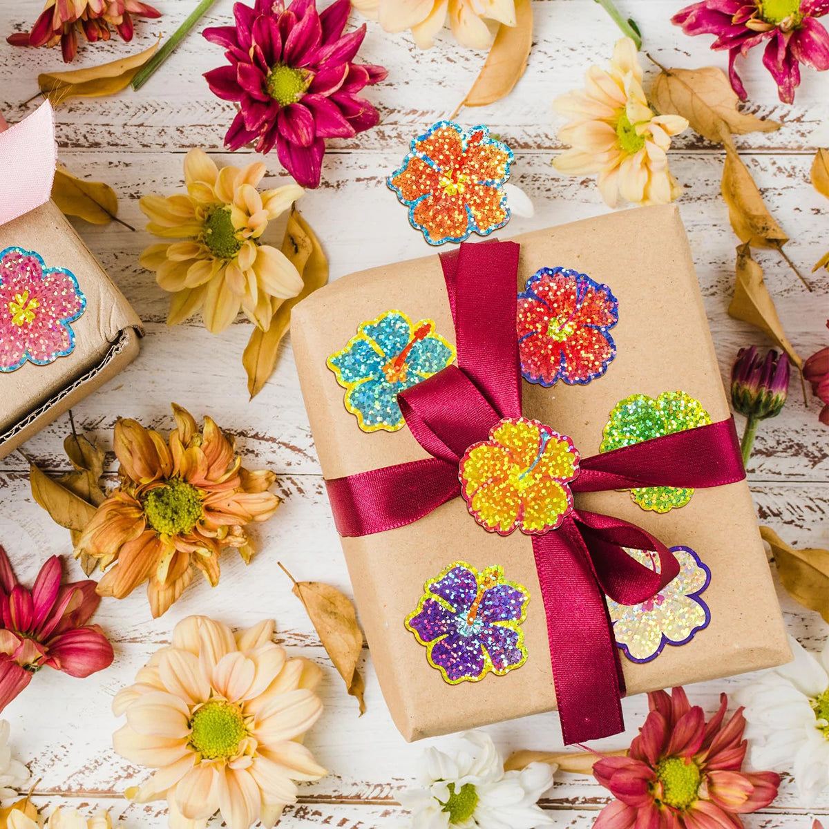 A collection of glitter flower round stickers in various colors scattered on a wooden surface.