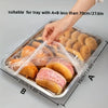 A hand places a clear elastic food cover over baked goods in a rectangular tray.