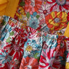 A close-up of a baby girl's floral print dress with matching yellow fabric details.