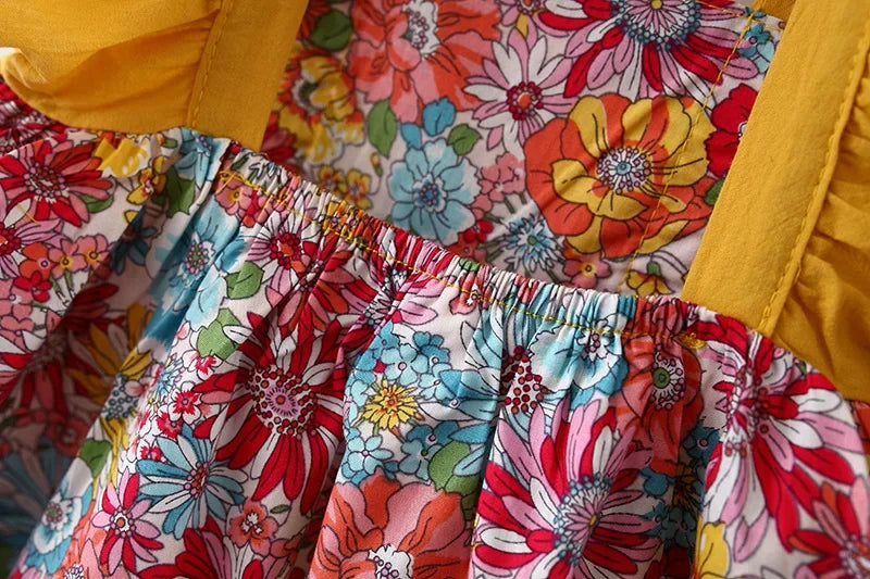 A close-up of a baby girl's floral print dress with matching yellow fabric details.