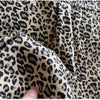 Close-up of a beige leopard print denim fabric showing texture and stitching.