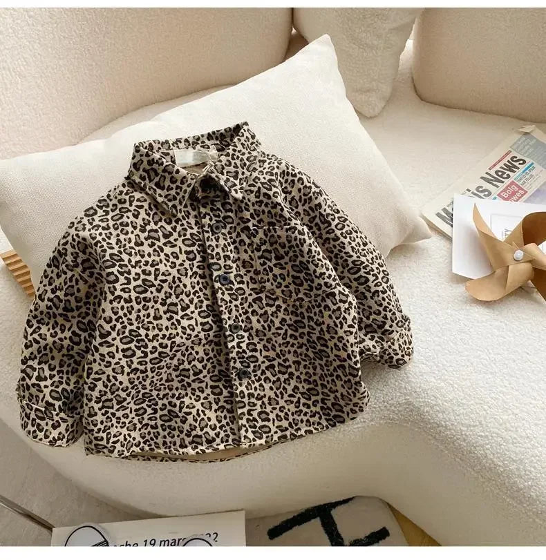 A leopard print denim jacket displayed on a white sofa cushion.
