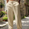 Hombre con pantalones casuales de mezcla de algodón color beige, de corte holgado, de pie sobre un camino de piedras.