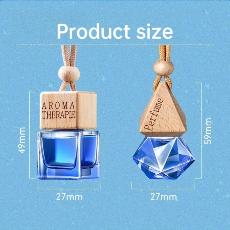 Hengende parfymeflaske i glass med trepyramidetopp og gullsnor, ved siden av firkantet aromaterapiflaske.