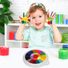 A smiling toddler holds up colorful fingers painted with paint, next to a palette of paint colors.