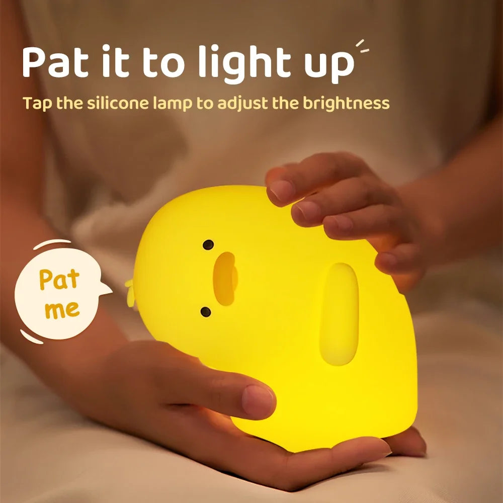 Una mano toca un patito de silicona amarillo con luz nocturna para ajustar el brillo.