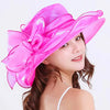 A woman wearing a bright pink wide brim organza sun hat with ruffled mesh