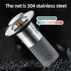 A silver press-type sink drain stopper with a stainless steel net filter is shown against a dark background.