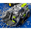 A gray and lime green transforming dinosaur car toy is shown resting on a surface covered with white plastic pellets.