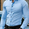 A man wearing a light blue long-sleeve formal shirt and black trousers, viewed from the chest up.