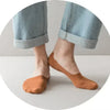 A pair of tan silicone grip no-show socks worn with light blue denim jeans.