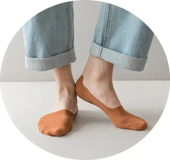 A pair of tan silicone grip no-show socks worn with light blue denim jeans.