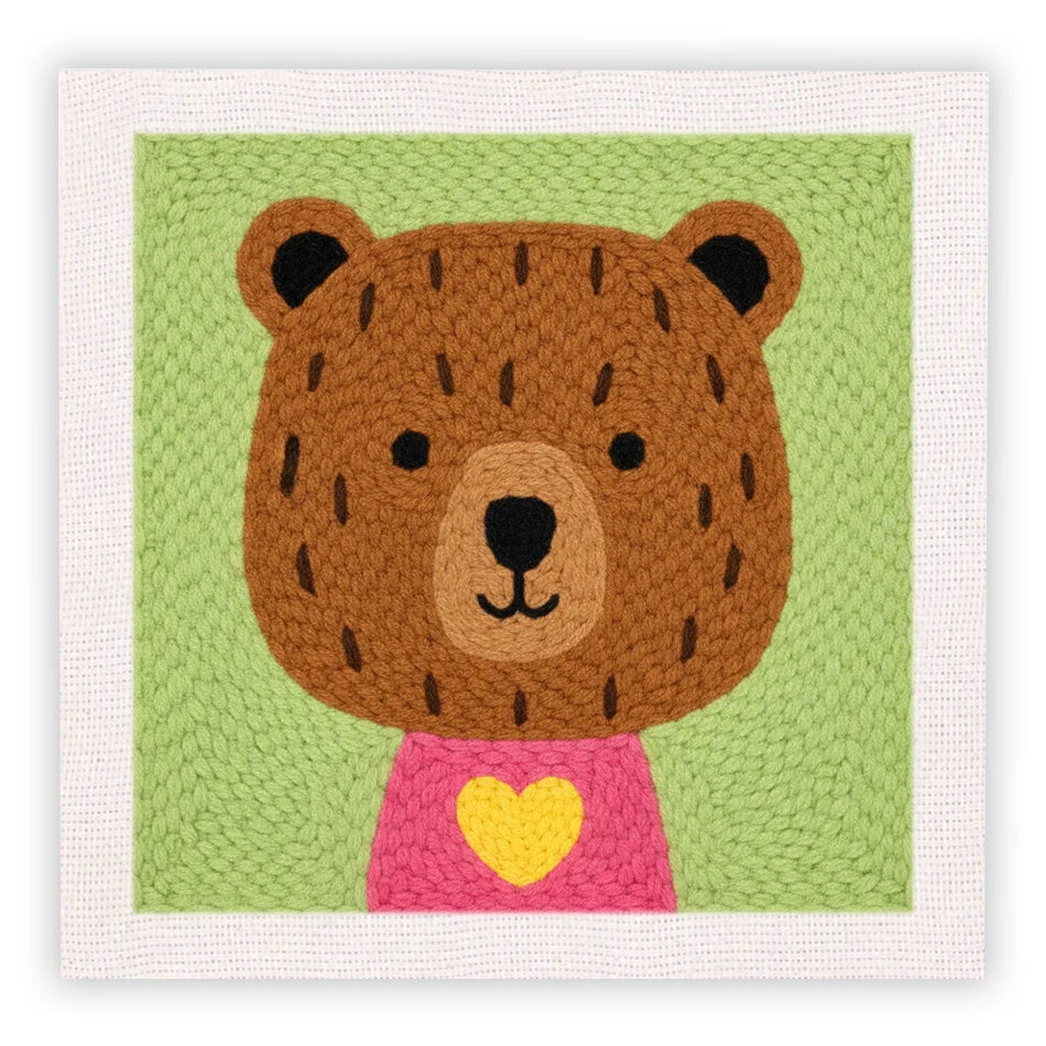 Oso de peluche tejido con orejas grandes, camisa rosa y corazón amarillo.