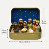 A miniature nativity scene featuring figures of Mary Joseph and baby Jesus set inside a gold-colored metal box with a blue st