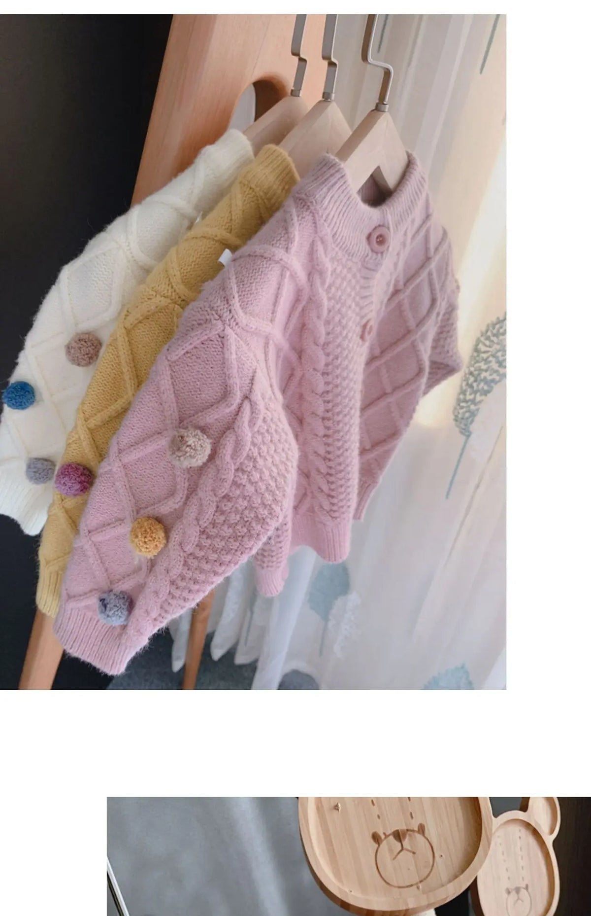 A display of various knitted cardigan sweaters in pastel colors, including cream, yellow, and pink, hanging on a wooden rack.