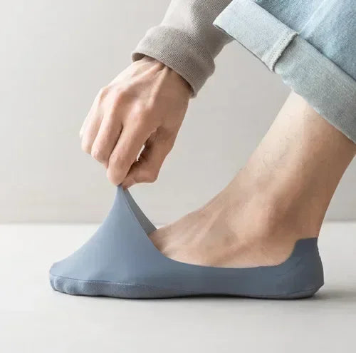 A person's foot is shown wearing a blue silicone grip no-show sock.
