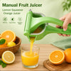 En hånd presser appelsinjuice fra en grønn manuell fruktpresse ned i et glass, med ferske sitrusfrukter ved siden av.