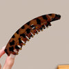 Mujer sostiene una pinza de banana acrílica esmerilada con estampado de leopardo en marrón y negro.